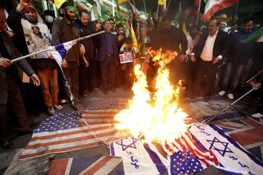 Iranians burn Israeli and US flags during a protest at Palestine square in Tehran, on April 1, 2024