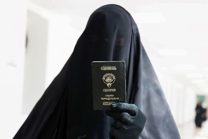 A Kuwaiti displays her passport as proof of identity before voting