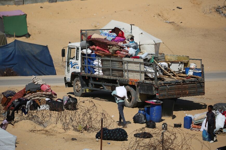 Displaced Palestinians gather their belongings on the back of a truck as they flee al-Mawasi to a safer area in Rafah in the southern Gaza Strip