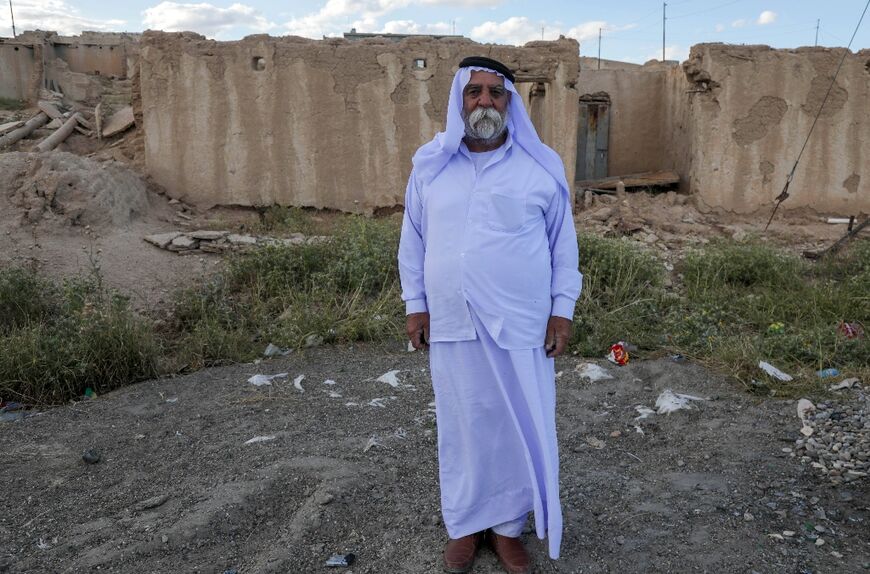 An Iraqi Yazidi man stands in front of a building destroyed during the 2014 attack by Islamic State fighters and the battles that followed, in the village of Solagh in the Sinjar region