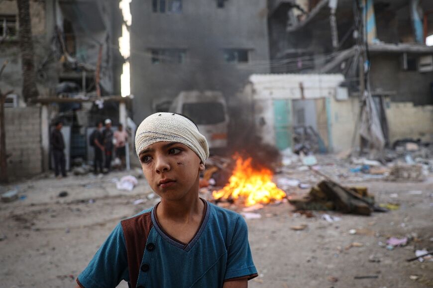An injured Palestinian boy stands next to the rubble of a family house that was hit by Israeli bombardment in the Tal al-Sultan neighbourhood of Rafah