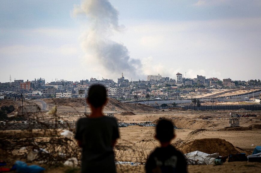 Boys watch smoke billowing during Israeli strikes east of Rafah in the southern Gaza Strip on May 13, 2024