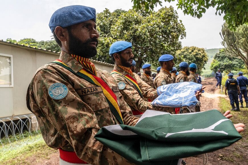 Pakistani peacekeepers hold the Pakistani and UN flags at the United Nations Organization Mission for the Stabilization of the Congo base during a handover ceremony to the local police