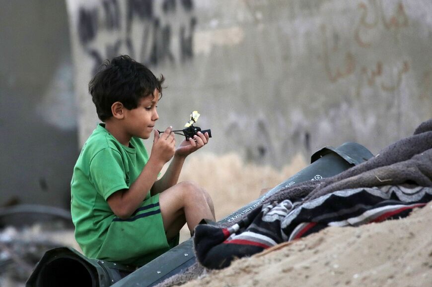A Palestinian child plays next to empty ammunition containers in Khan Yunis
