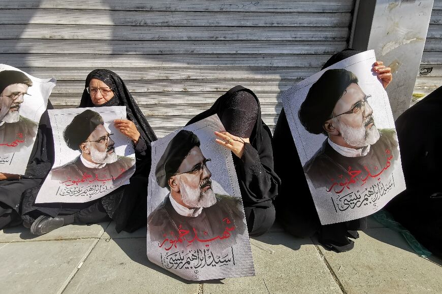 Mourners hold posters of Iranian president Ebrahim Raisi, killed in a helicopter crash, during his funeral procession in Tehran