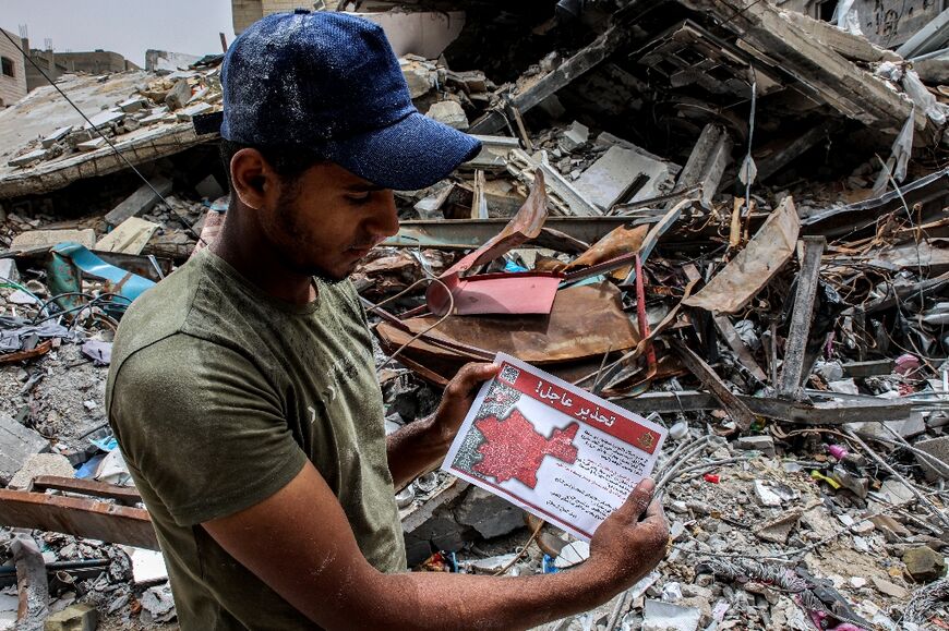 A Palestinian man holds a flyer dropped by the Israeli military over northern Gaza, urging people to "temporarily evacuate" due to the fighting
