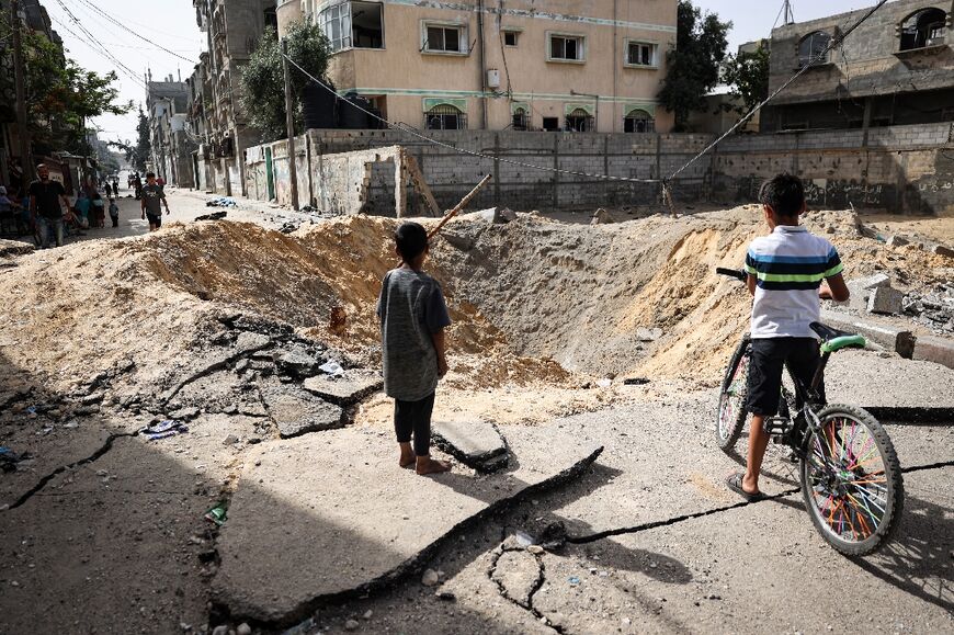 Children stand near a crater caused by Israeli bombardment in a street in Rafah in the southern Gaza Strip