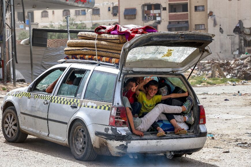 Children gesture as they sit in the back of a vehicle arriving at the Daraj quarter of Gaza City on May 11