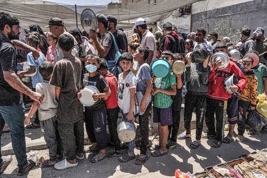 Men, women and children queue to receive food rations from a public kitchen in Deir el-Balah in the central Gaza Strip on May 13, 2024 