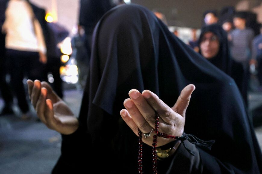 An Iranian woman prays for President Ebrahim Raisi 