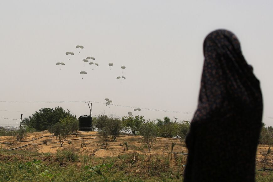 A Palestinian woman watches as humanitarian aid is airdropped over Khan Yunis in the southern Gaza Strip on May 23, 2024