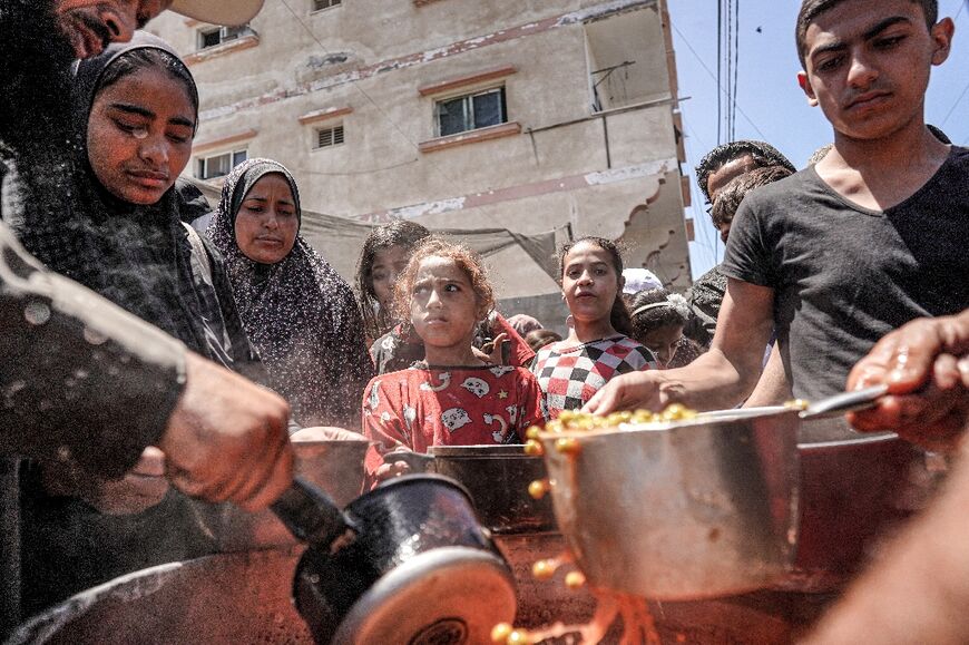 People are handed food portions at a public kitchen in Deir el-Balah in the central Gaza Strip 