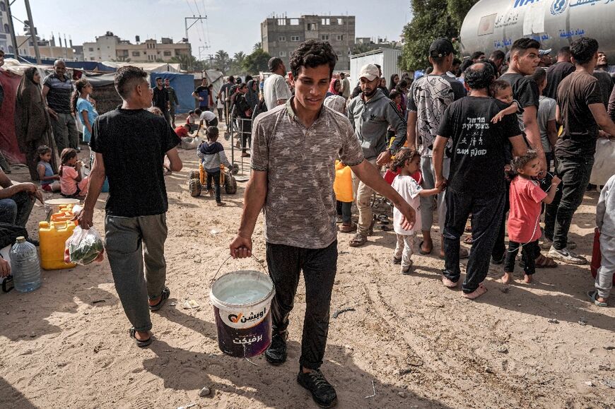 A youth walks with a bucket of water from a tanker cistern in Deir el-Balah in the central Gaza Strip on April 30, 2024