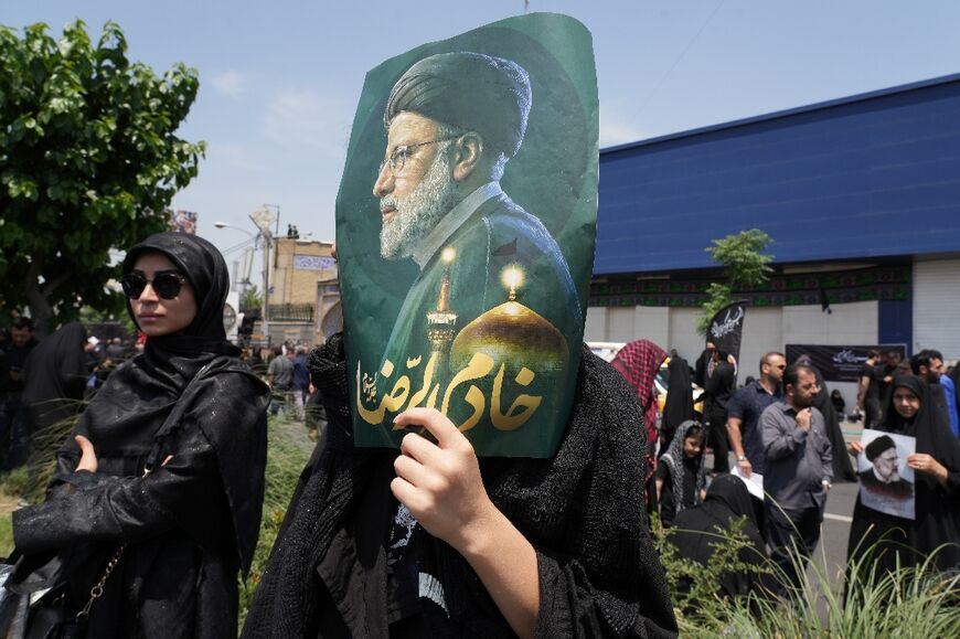 A woman mourner in Tehran carries a portrait of the late president