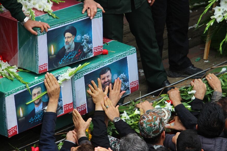 Mourners reach out to touch the coffins as the funeral procession passes through the streets of Tabriz