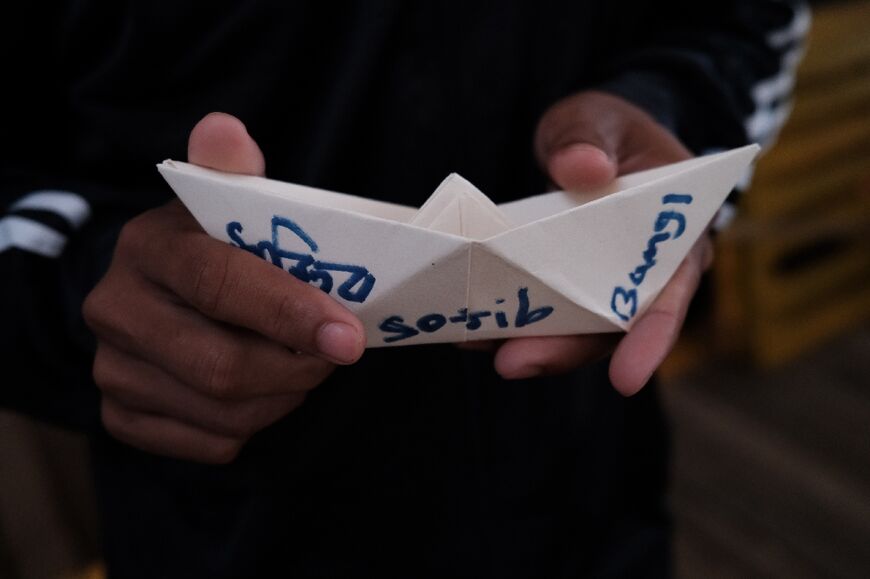 Sojib, un jeune migrant du Bangladesh, tient un bateau en papier qu'il a fabriqué, à bord du navire-ambulance Ocean Viking affrété par l'ONG SOS Méditerranée, le 21 mai 2024.