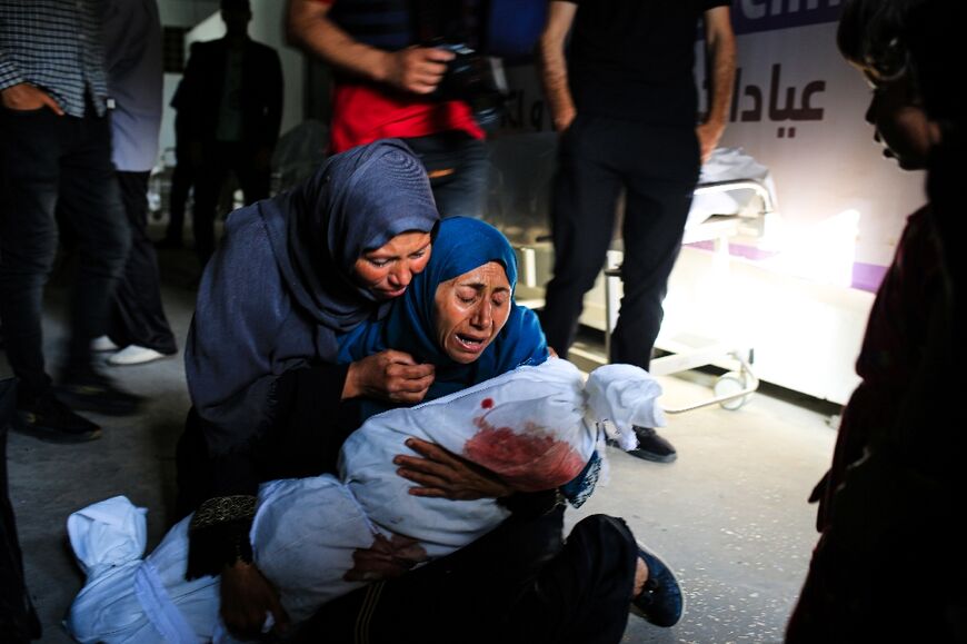 Palestinian women mourn the shrouded body of a child killed in the attack on the camp