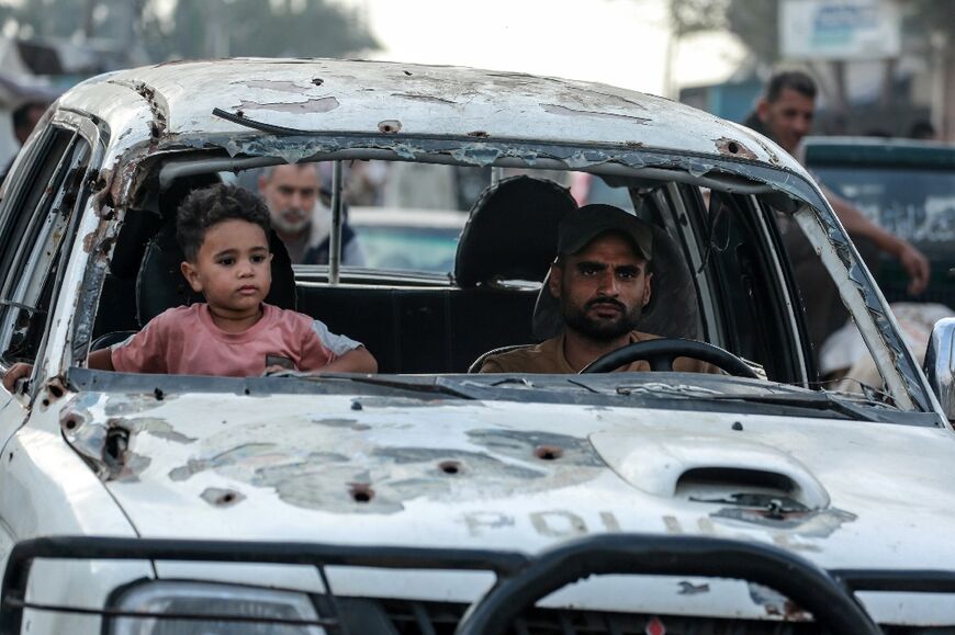 A Palestinian child sits next to a man driving a damaged car in Deir el-Blaha in the central Gazas Strip