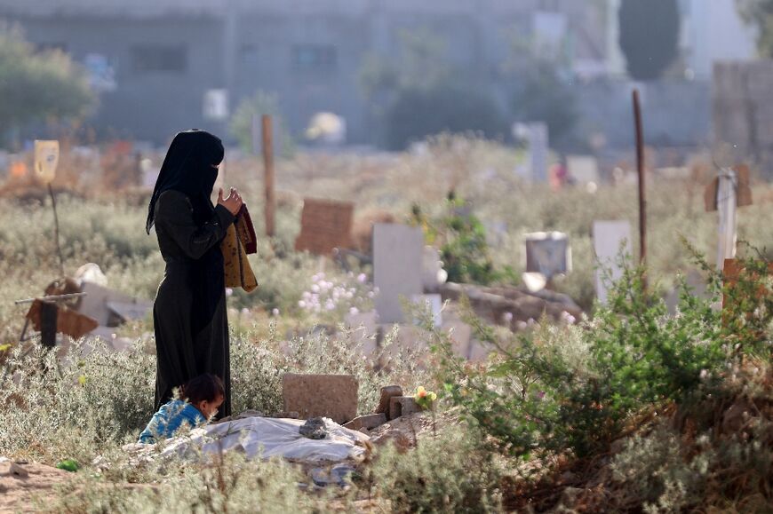 A Palestinian woman in Gaza City prays near the grave of a relative killed in the ongoing conflict between Israel and the Hamas movement 