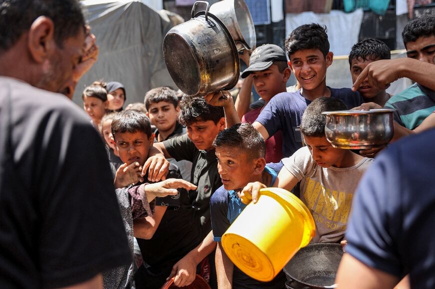 Children queue in Jabalia refugee camp to receive food aid from a kitchen at the Abu Zeitun school run by UNRWA, the UN agency for Palestinian refugees