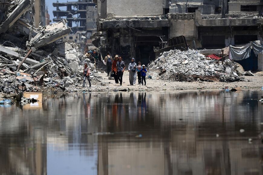 Palestinians walk near a puddle of stagnant water in Khan Yunis, southern Gaza -- the UN says Gaza's water and sanitation infrastructure has sustained 'significant damage' 