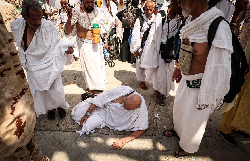 A man affected by the scorching heat sits on the ground at the site of the symbolic 'stoning of the devil' ritual in Mina