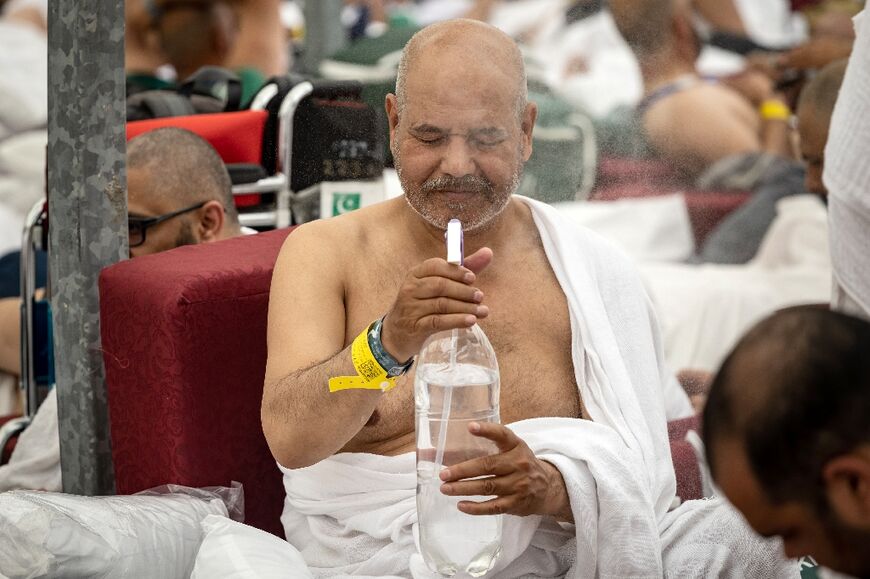 A Muslim pilgrim sprays his face with water to cool down at the Mina tent during the hajj