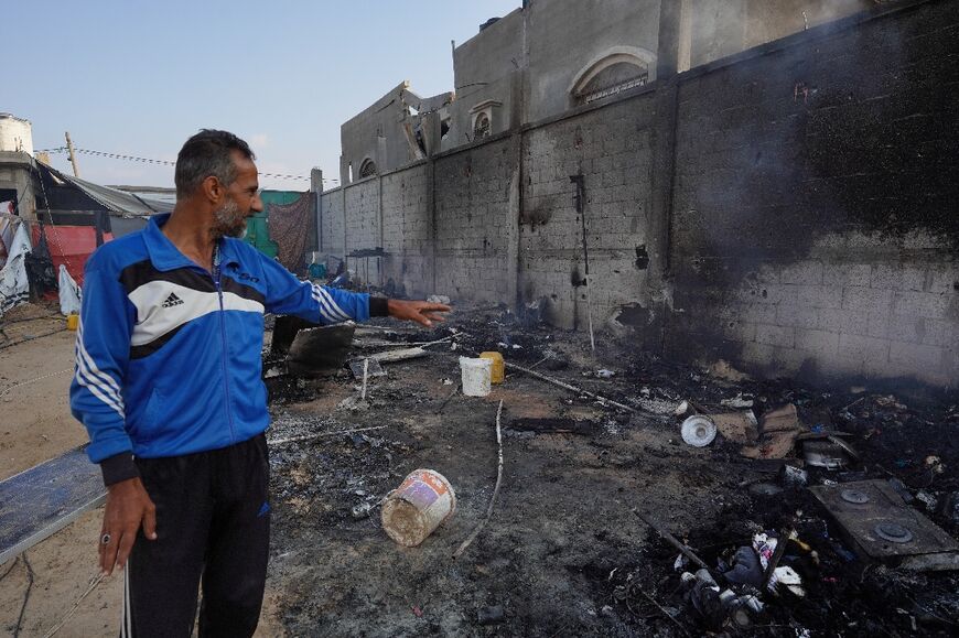 A Palestinian man points to ashes in a tented area of Al-Mawasi, southern Gaza, the day after a deadly strike in the area