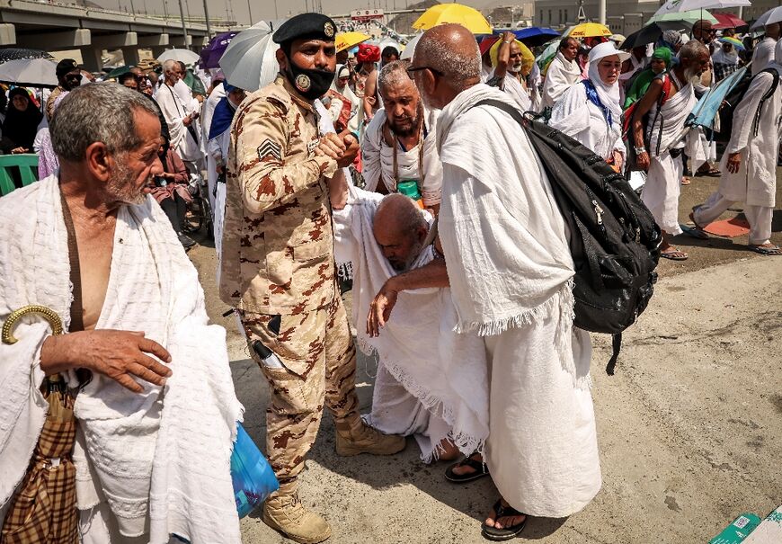 A policeman and other pilgrims help a worshipper affected by the scorching heat