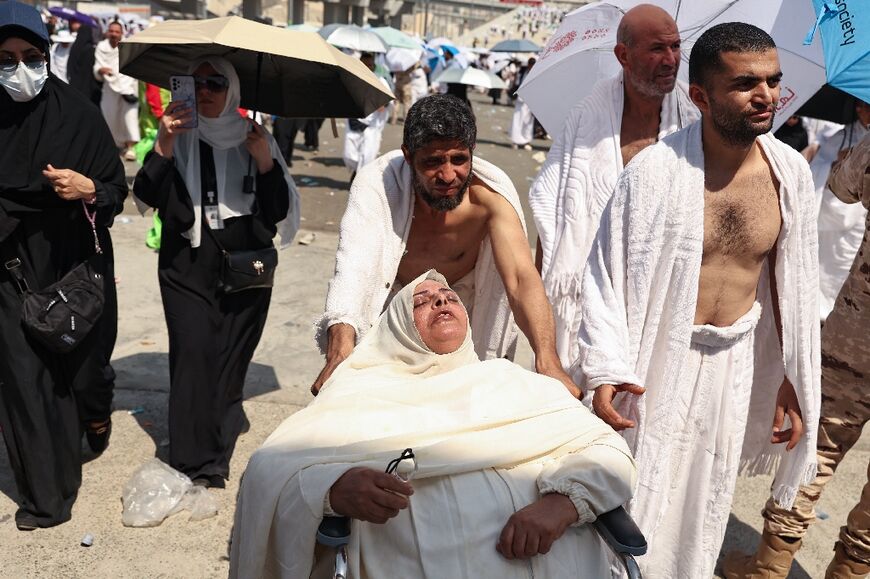 A woman affected by the heat heat is pushed away on a wheelchair in Mina