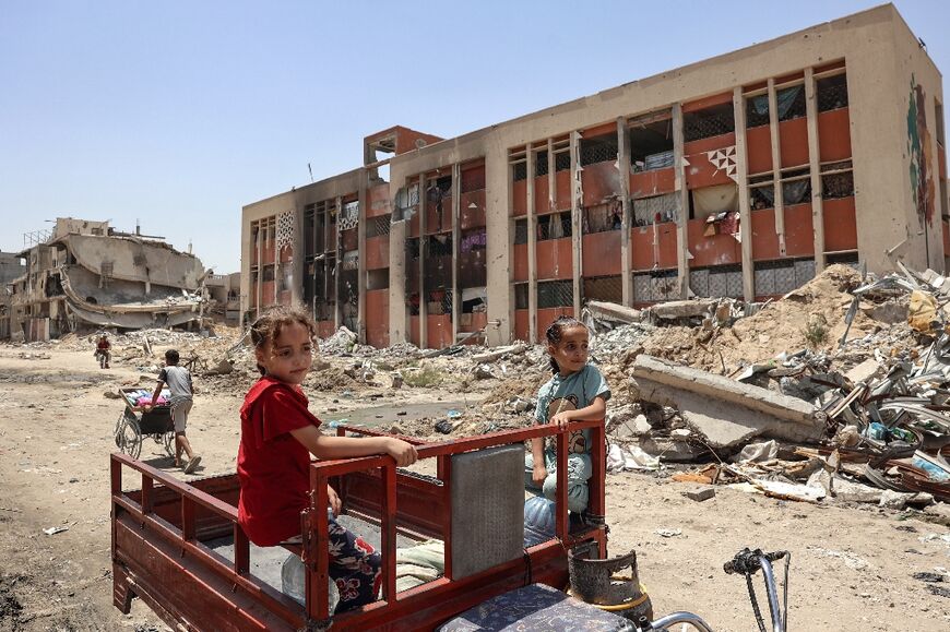 Palestinian children ride past a damaged school in Khan Yunis -- a UN-backed organisation estimated that more than 75 percent of Gaza schools would need full reconstruction or major rehabilitation