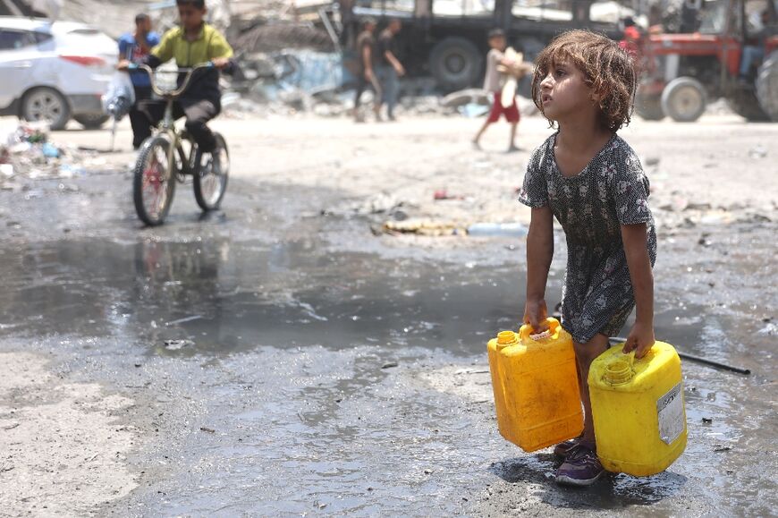 A Palestinian girl carries water containers in Jabalia refugee camp in the northern Gaza Strip on June 3, 2024