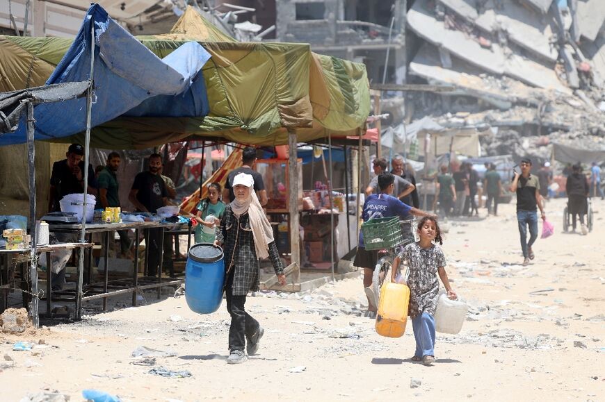 Palestinian girls carry water containers in the Jabalia refugee camp, in the northern Gaza Strip