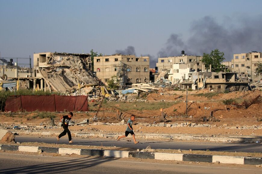 Palestinian boys run as smoke billows during Israeli bombardment east of Bureij refugee camp in central Gaza