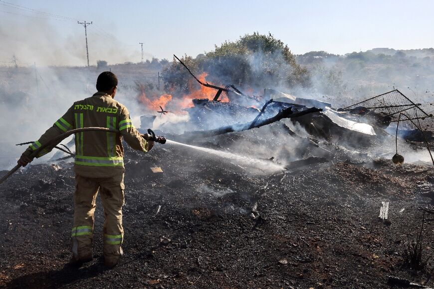 An Israeli firefighter battles flames on the outskirts of Kiryat Shmona