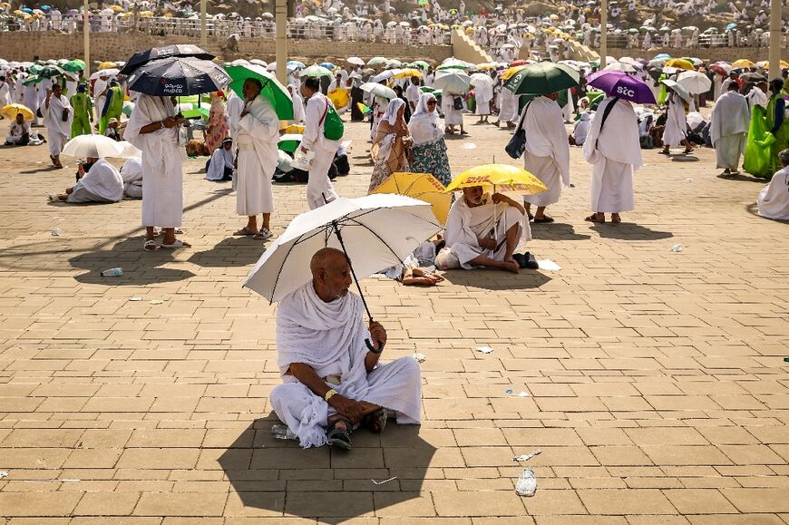Muslim pilgrims use umbrellas to shade themselves from the sun as they arrive at the base of Mount Arafat during the hajj