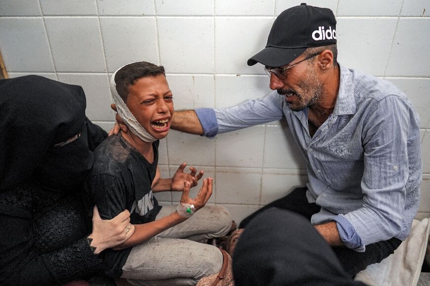 An injured boy mourning the loss of his father in a strike on central Gaza's Maghazi refugee camp, at a hospital morgue