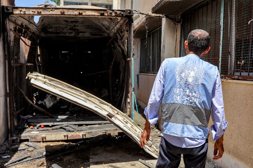 A UN worker inspects the remains of a container hit by Israeli bombardment at a school in Gaza's Al-Shati refugee camp