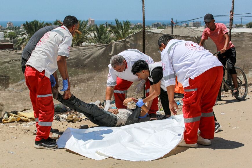 Palestine Red Crescent paramedics wrap the body of a man killed during bombardment northwest of Rafah 