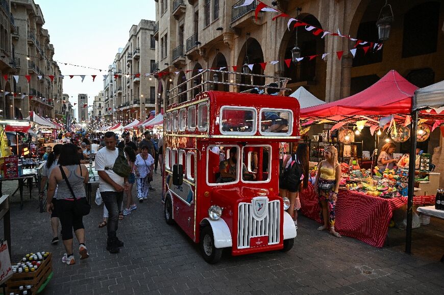 A vehicle decorated like a double decker bus drives near revelers during the Beirut Street Festival in downtown Beirut