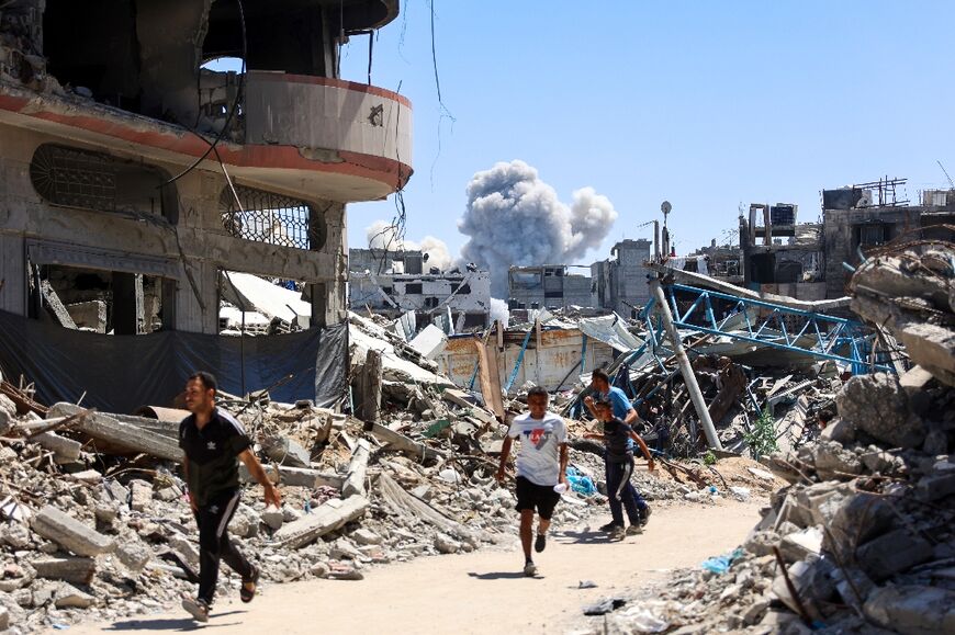 People run for cover as smoke billows over Gaza City's Shejaiya district after Israeli bombardment 