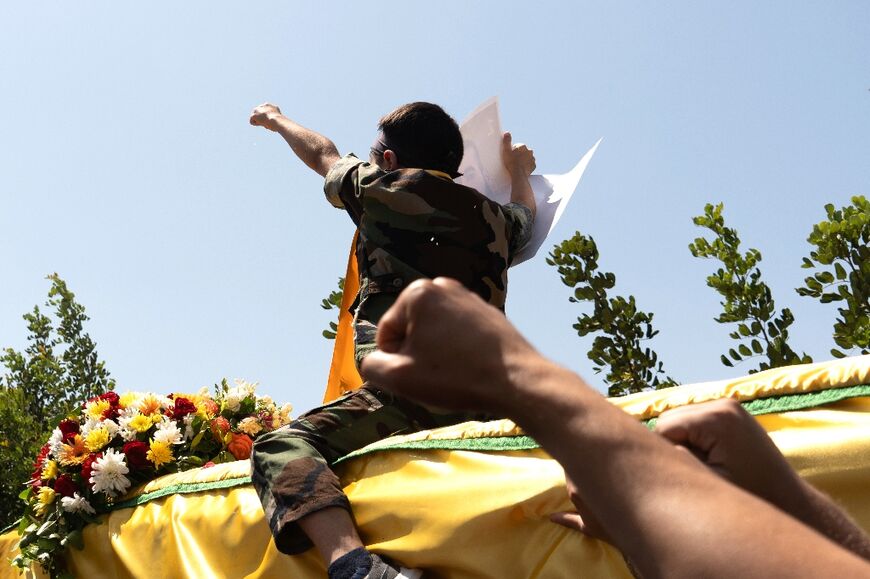 Mahdi, the son of killed Hezbollah fighter Wehbi Mohammed Ibrahim, sits on his father's coffin during his funeral in the village of Kfar Kila, southern Lebanon 