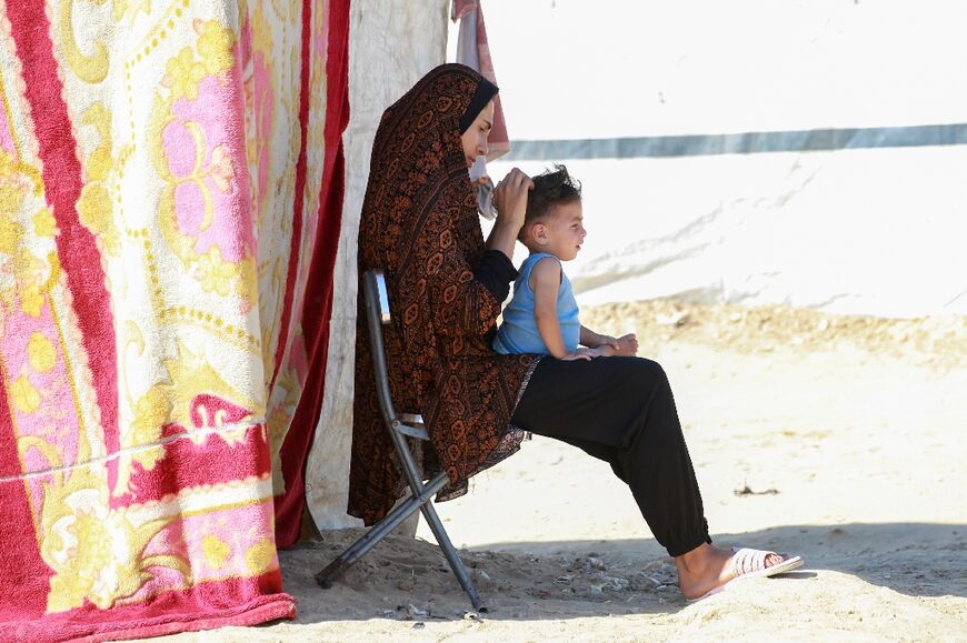 A Palestinian woman sits with a child at a camp for displaced people in Deir al-Balah, in the central Gaza Strip
