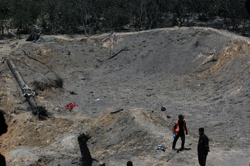 Palestinians look at a huge crater in the sand following an Israeli military strike on the al-Mawasi camp for displaced people in the Gaza Strip 