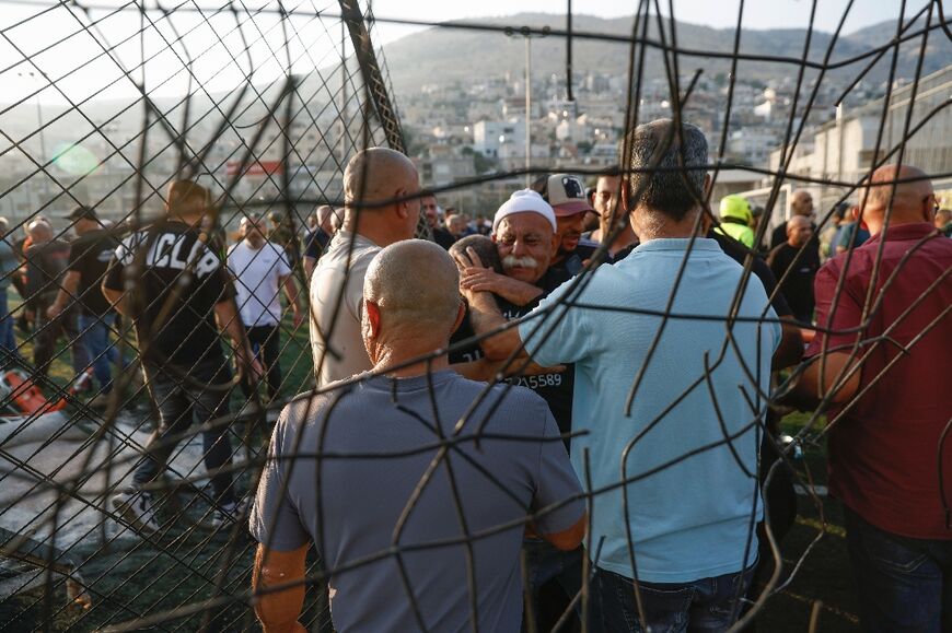 Residents of Majdal Shams comfort each other after a rocket fired from Lebanon creates carnage on a football pitch in the town in the Israeli-annexed Golan Heights