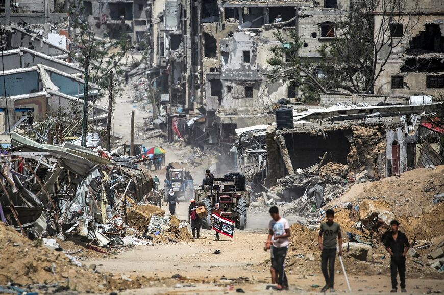 A tractor loaded with cisterns drives through destroyed buildings in Khan Yunis in the southern Gaza Strip