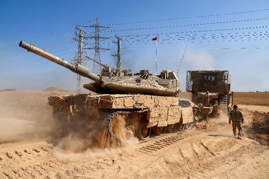 A bulldozer tows an Israeli tank near Israel's southern border with the Gaza Strip