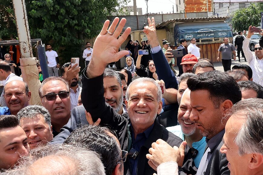 Reformist candidate Masoud Pezeshkian waves to supporters outside a polling station in Tehran