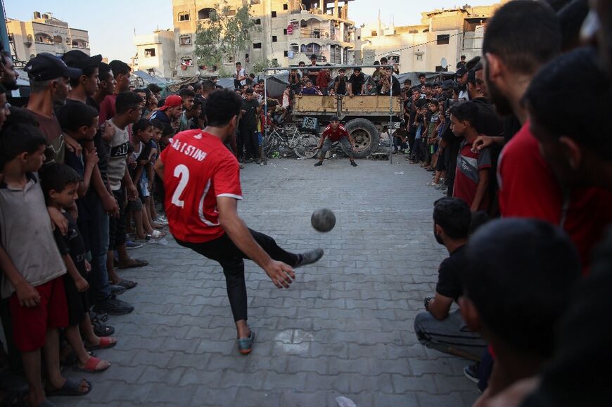 A crowd watches on as a footballer takes a penalty in Gaza's Jabalia refugee camp