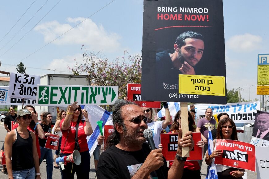 Yehuda Cohen raises a placard bearing a picture of his hostage son Nimrod Cohen as he takes part in a rally near an Israeli minister's home